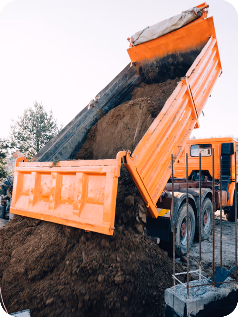 Kipper lädt Erdaushub auf einer Baustelle ab.